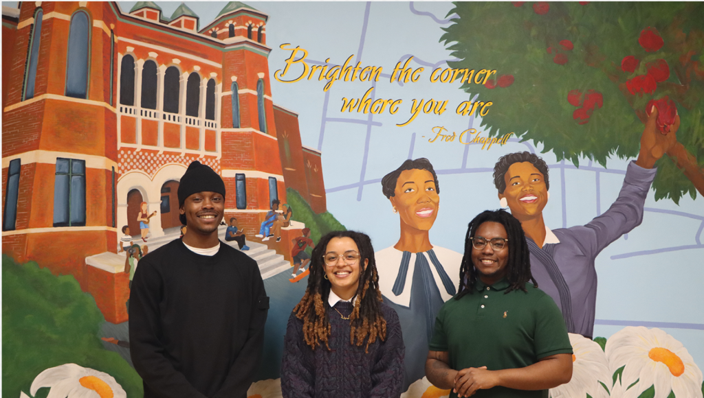 Aminah Coppage, Jalani Maxwell, and Myles Wilder stand before the mural they created in the Dean's office.